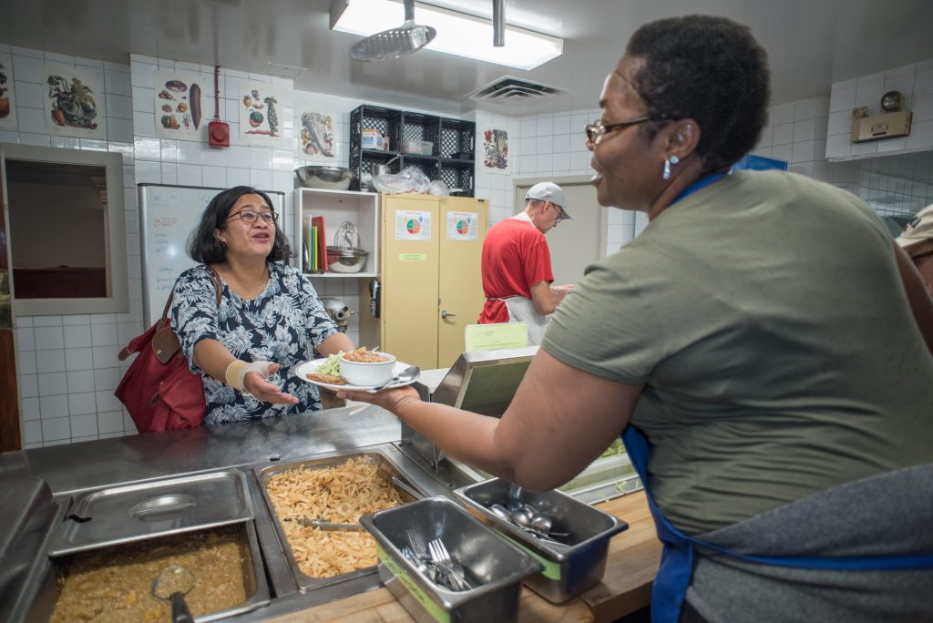 La cheffe invitée Joke sert du riz jollof aux membres de la communauté lors d’un repas du Resto Dépôt.