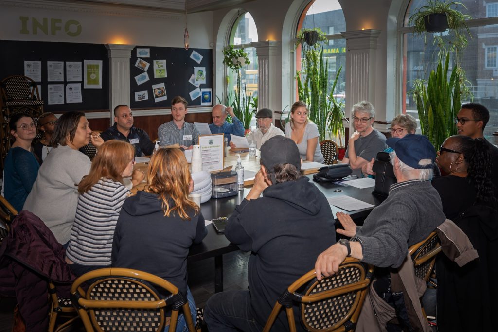 Community members speak with election candidates during a 2025 Eat Think Vote event at The Depot about food insecurity and community priorities.