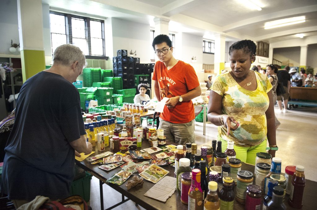 A volunteer supports participants at The Depot's former food bank, where available foods consisted primarily of donated shelf-stable items such as canned goods, condiments, and dried soup packages.