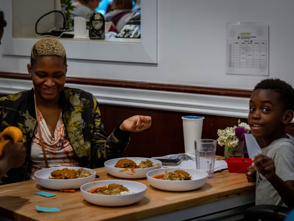 Volunteers serve meals directly to participants during a Resto Depot community meal.